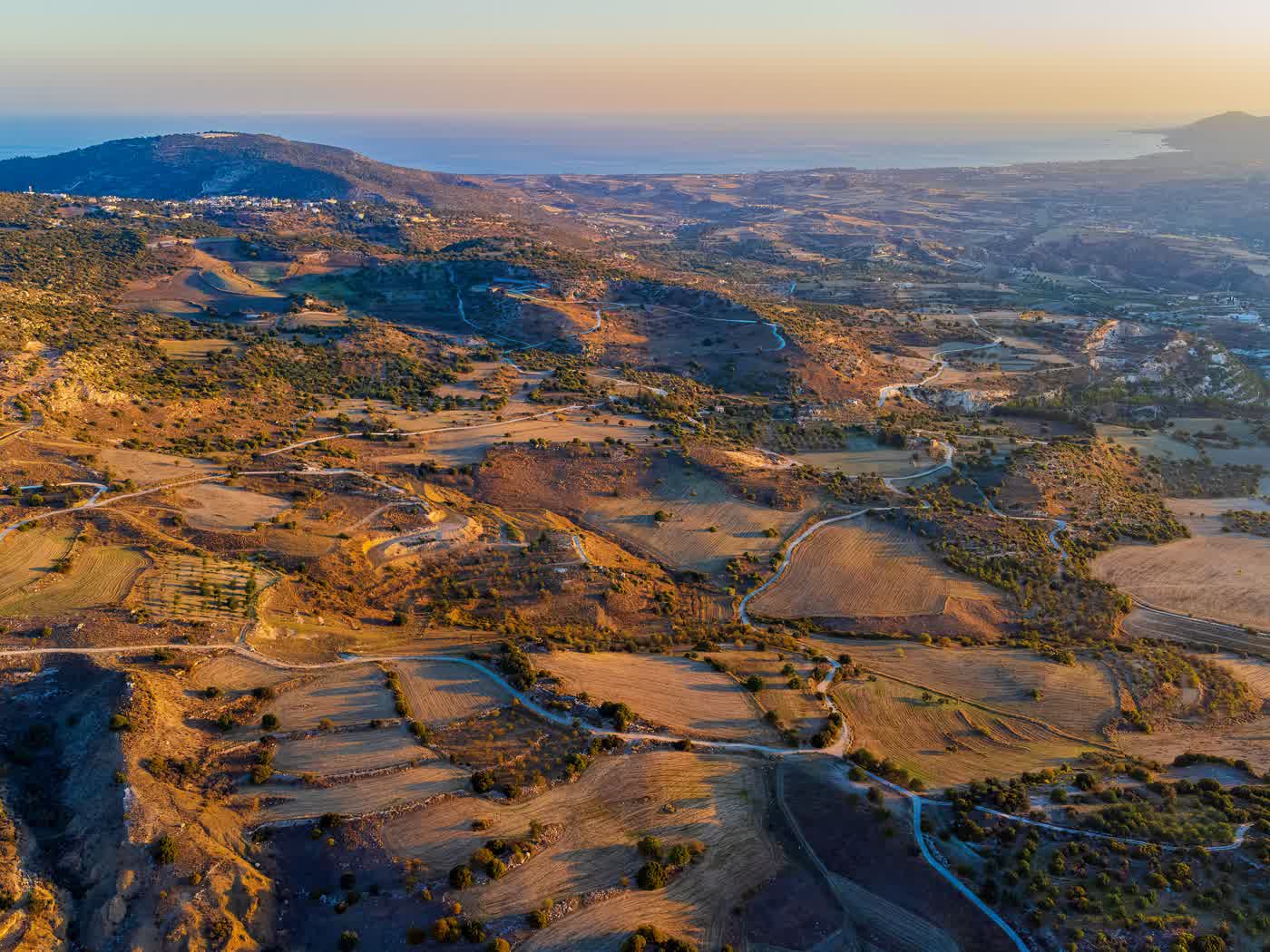 Golden evening light over Cyprus countryside stretching down to the sea